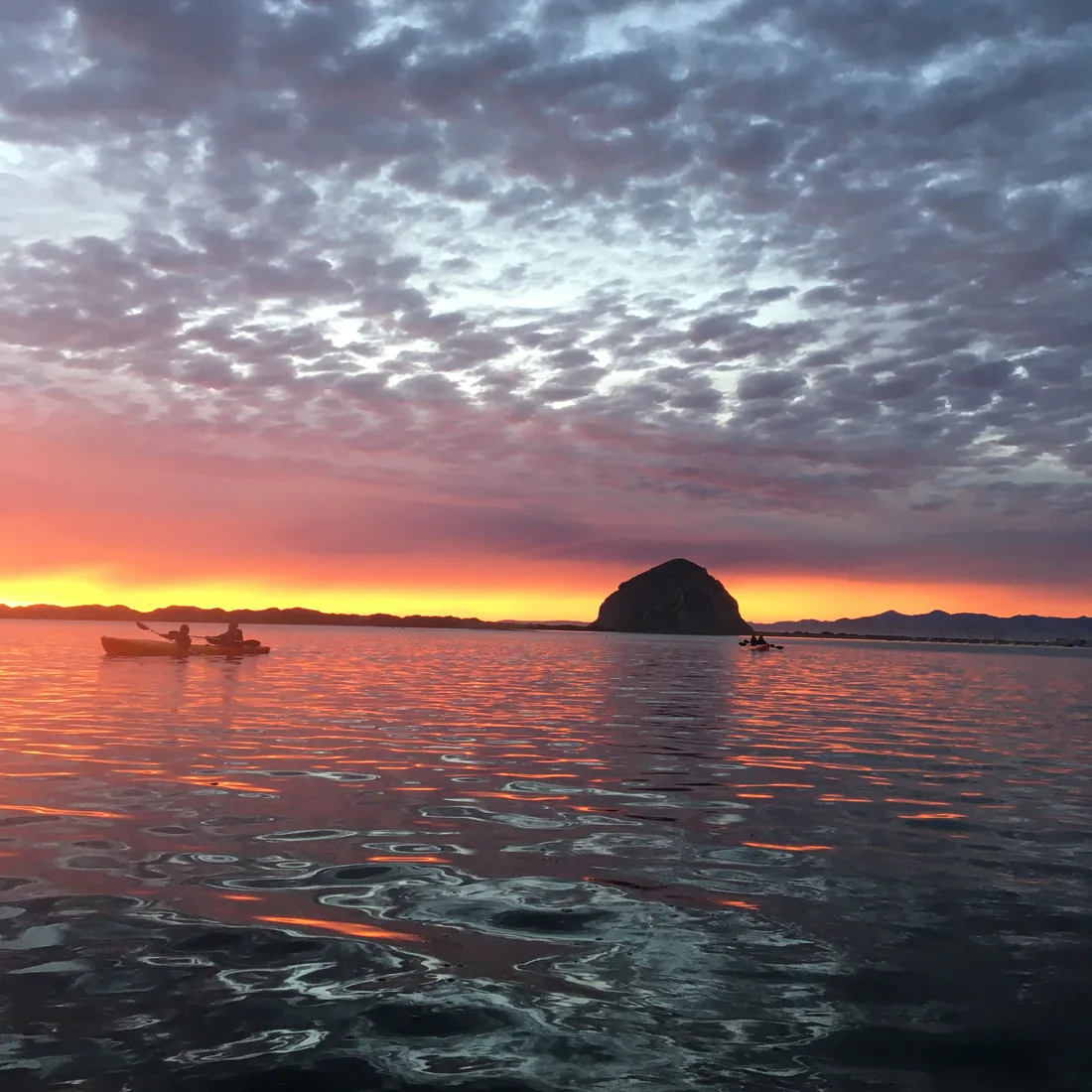 Kayakers at sunset on Morro Bay beneath Morro Rock